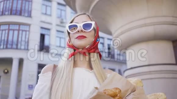 站在街上拿着刚烤好的面包和羊角面包的时尚年轻女人的肖像时尚迷人视频的预览图