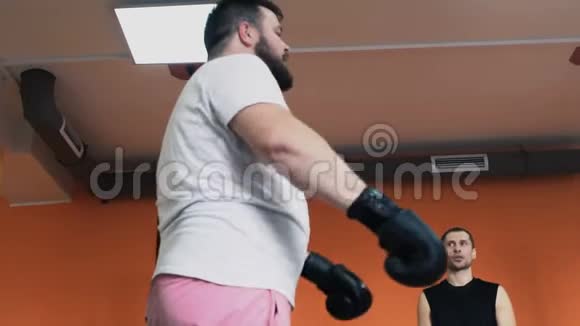 拳击训练胖子和苗条的女孩戴着手套互相问候私人教练健身房个人减肥训练视频的预览图