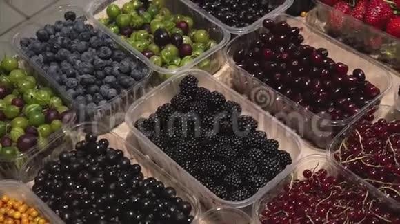 将新鲜的有机浆果混合在市场上准备出售的塑料盒子里视频的预览图