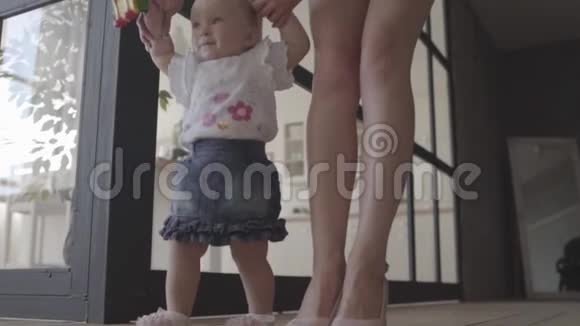 不认识的女人和她的女婴站在家里的地板上孩子迈出第一步妈妈支持她妈妈视频的预览图