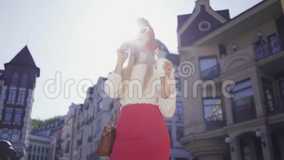 时尚女性带着一杯咖啡站在街上阳光下用手机说话有魅力的女孩视频的预览图
