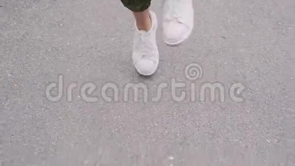 穿着白色运动鞋的时髦女孩正在公园里跳跃用便携式扬声器听音乐特写视频的预览图