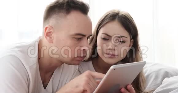 一对在床上使用数码平板电脑的夫妇视频的预览图