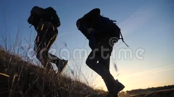 两名游客团队合作背包慢动作行走在夕阳的阳光下走着剪影二视频的预览图