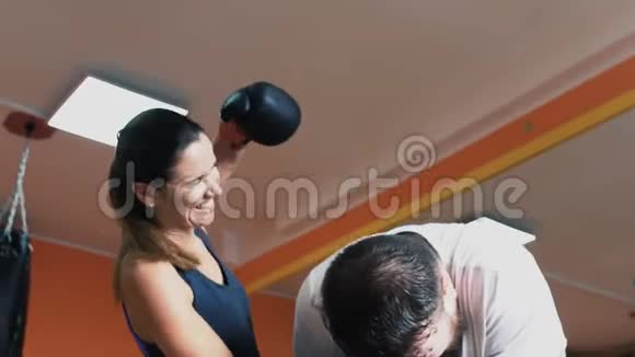 一个身材苗条的女孩和胖男人在一起在健身房玩得很开心女人用拳击手套打一个丰满的出汗男人个人体重视频的预览图