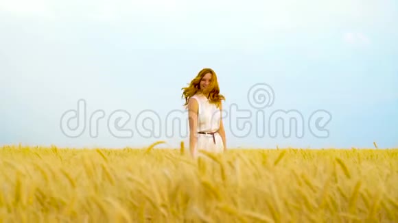 年轻活泼的红发女人对着镜头微笑躲在麦田里视频的预览图