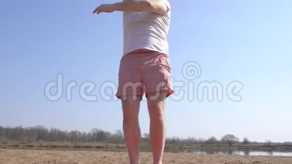 一个留着胡子的白种人正在河畔的沙滩上做动态瑜伽这是他的延伸视频的预览图