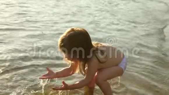 宝宝在水中飞溅泼水可爱的孩子在海滩上快乐地玩耍快乐的孩子在日落时洗澡视频的预览图
