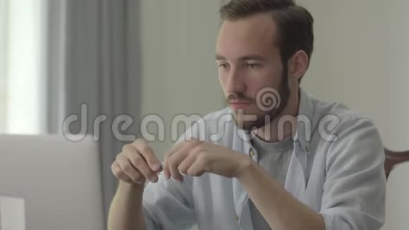 年轻英俊的男人愤怒地在办公室里坐在电脑前折断铅笔的肖像存在的问题视频的预览图