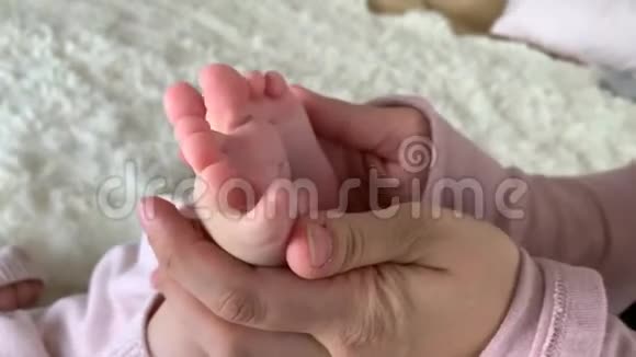母亲温柔地抱着小女儿的腿做一个轻脚按摩玩耍健康的生活方式快乐的父母视频的预览图
