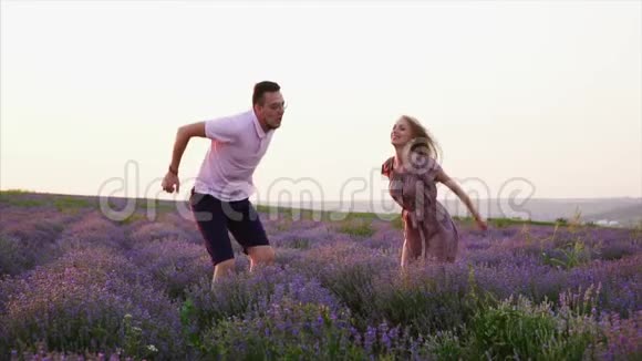 年轻夫妇在开花薰衣草地跳跃动作缓慢视频的预览图