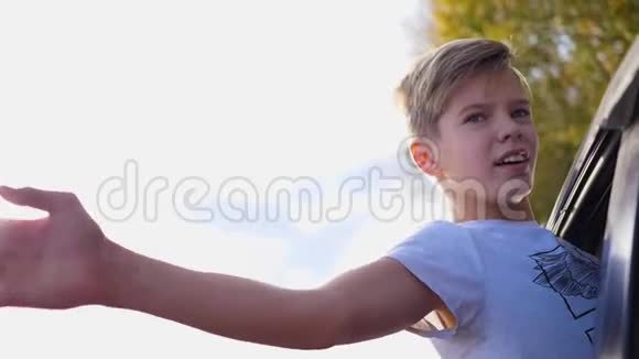 少年男孩望着车窗外挥手汽车正在乡间小路上行驶视频的预览图