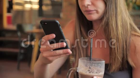 一个女孩的特写肖像女性喝一杯鸡尾酒拍一部4k的智能手机视频的预览图