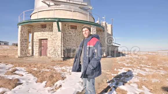 一位穿着牛仔裤和保暖制服的男性研究员在一个冬天阳光明媚的日子里在一个科学建筑的背景下视频的预览图