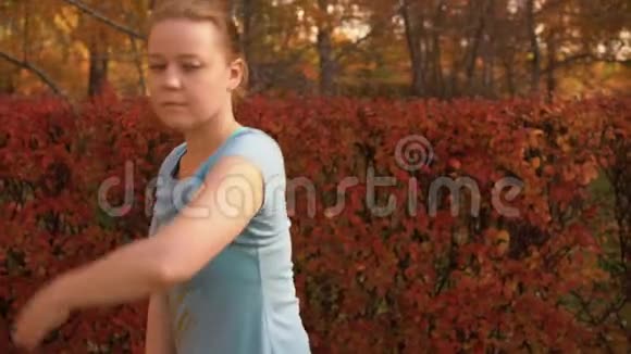 微笑的年轻女子在秋天公园跳舞视频的预览图