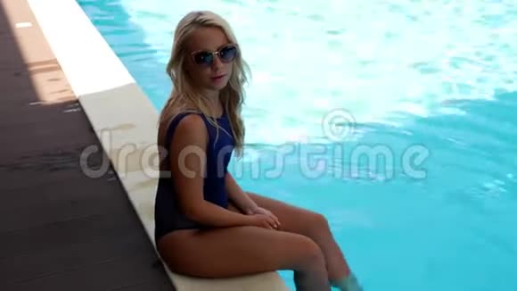 穿着蓝色泳衣的女孩在游泳池里溅起双腿视频的预览图