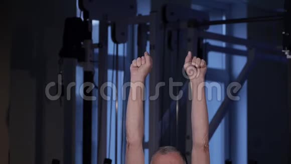 一个同龄的人在健身房为手指做关节体操握紧松开拳头双手向上副本视频的预览图