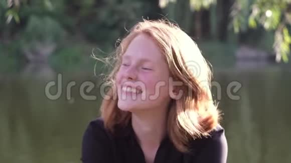 年轻的红头发女孩微笑着看着前面的学生视频的预览图