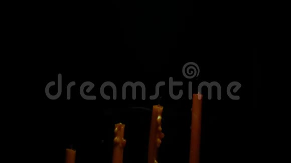 女人的手在点燃蜡烛后熄灭的蜡烛与烟雾在黑色的背景抽象背景的概念视频的预览图