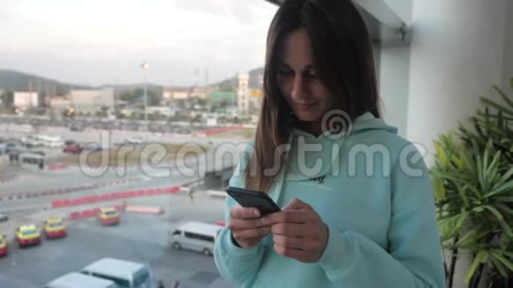 年轻女子正在窗边等她的航班女性点击智能手机4k视频的预览图