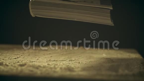 一本书在一张尘土飞扬的木桌上落下特写镜头视频的预览图