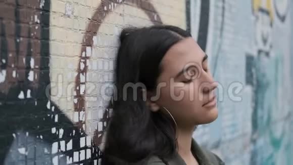 伤心的黑发女孩用涂鸦滑下墙视频的预览图