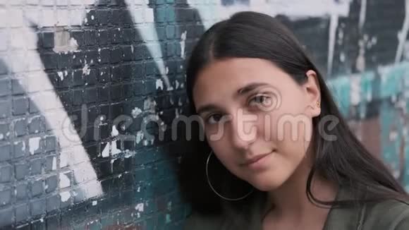 时髦的黑发女孩站在墙边涂鸦和悲伤地把头靠在墙上视频的预览图
