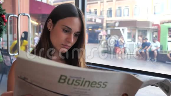 坐在咖啡馆里看报纸的年轻女子视频的预览图