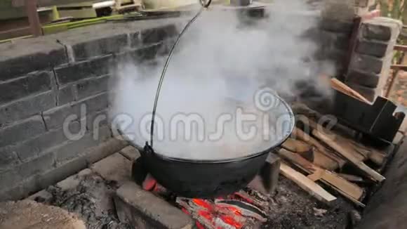 在火上面的大锅里煮排骨蒸汽和气味在盖子下面留下那个人把木头放好视频的预览图