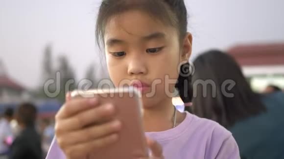 孩子们在晚上的户外聚会上小女孩并使用智能手机视频的预览图