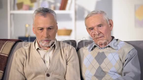 坐在沙发上看镜头的沮丧老人社会不安全视频的预览图