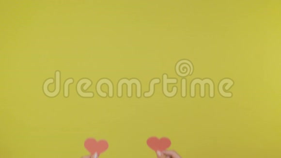 女执手小红心随着音乐节奏舞蹈隔离在黄橙色背景上视频的预览图