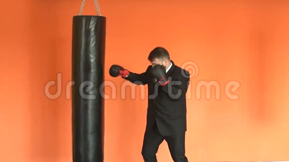 穿黑色西装的愤怒商人在健身俱乐部缓解压力拳击手套的经理或老板打拳击视频的预览图