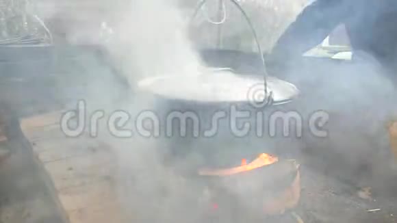 人把切碎的木头放在悬浮锅炉下面的明火上锅炉里的水和肉视频的预览图