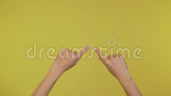 优雅的女性双手在4K的黄色背景上勾勒出心脏轮廓视频的预览图