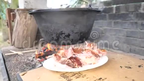 鲜熟的肉放在瓷盘上在烤架上烧火的大锅里吃完的肉视频的预览图