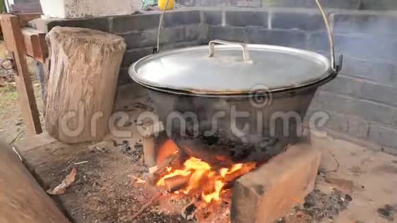 带手套的厨师用猪肉和骨头从锅炉上拆下盖子在火盆里做饭太过火了视频的预览图
