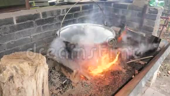 在烧烤炉上方的Keetle上的圆形景观大搪瓷锅肉汤挂在院子里视频的预览图