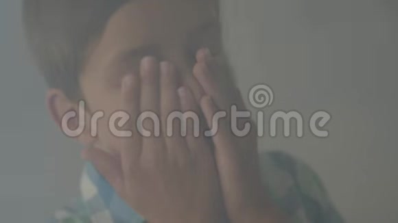 一个困惑害怕的男孩站在烟雾弥漫的房间里用手捂着脸咳嗽危险概念视频的预览图