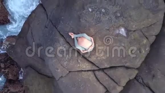 灵活的女士坐在巨大的石头上伸展瑜伽姿势视频的预览图
