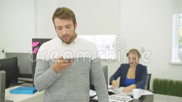 男人在电话里记录语音信息他身后的女人在设计房子视频的预览图