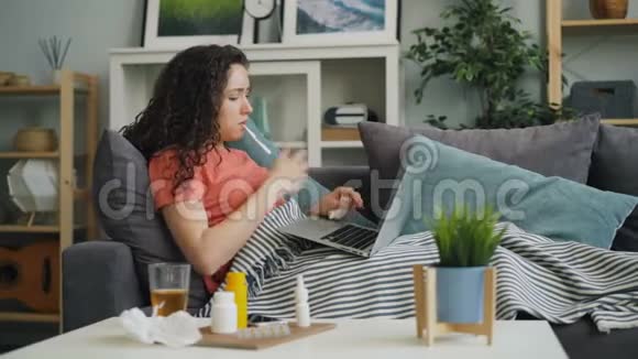 患病妇女检查体温服药使用笔记本电脑浏览症状视频的预览图