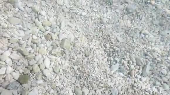 在清澈的波浪水中躺在海底的灰色卵石和石块视频的预览图