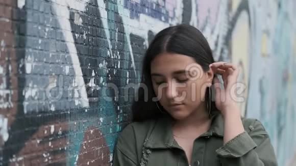 站在墙边一只手在头发上涂鸦可怜的小女孩靠在墙上视频的预览图