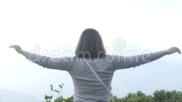 近镜头女人坐着伸出双臂在山顶慢动作视频的预览图
