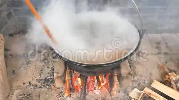 在水壶里用木勺搅拌汤在明火上混合熟肉视频的预览图