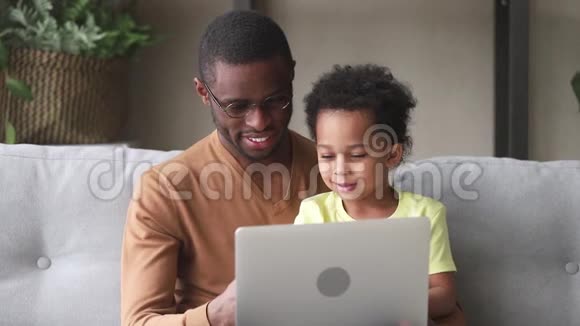 快乐的黑人父亲教孩子用笔记本电脑阅读视频的预览图