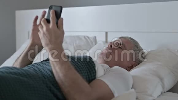 睡在床上的时候中年男人在说智能手机视频的预览图