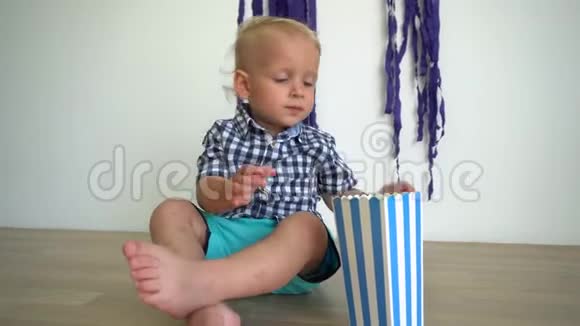 饥饿的小男孩在木地板上吃纸箱里的爆米花万向节运动视频的预览图