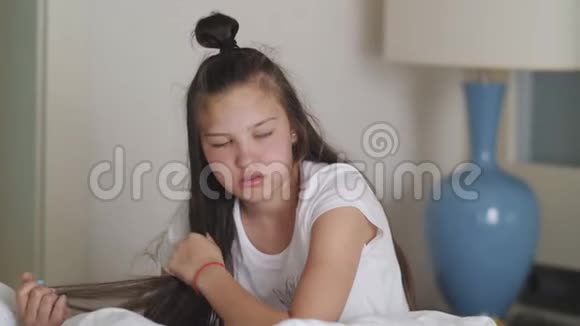 烦躁的困倦女孩坐在床上试图在睡眠后恢复视频的预览图
